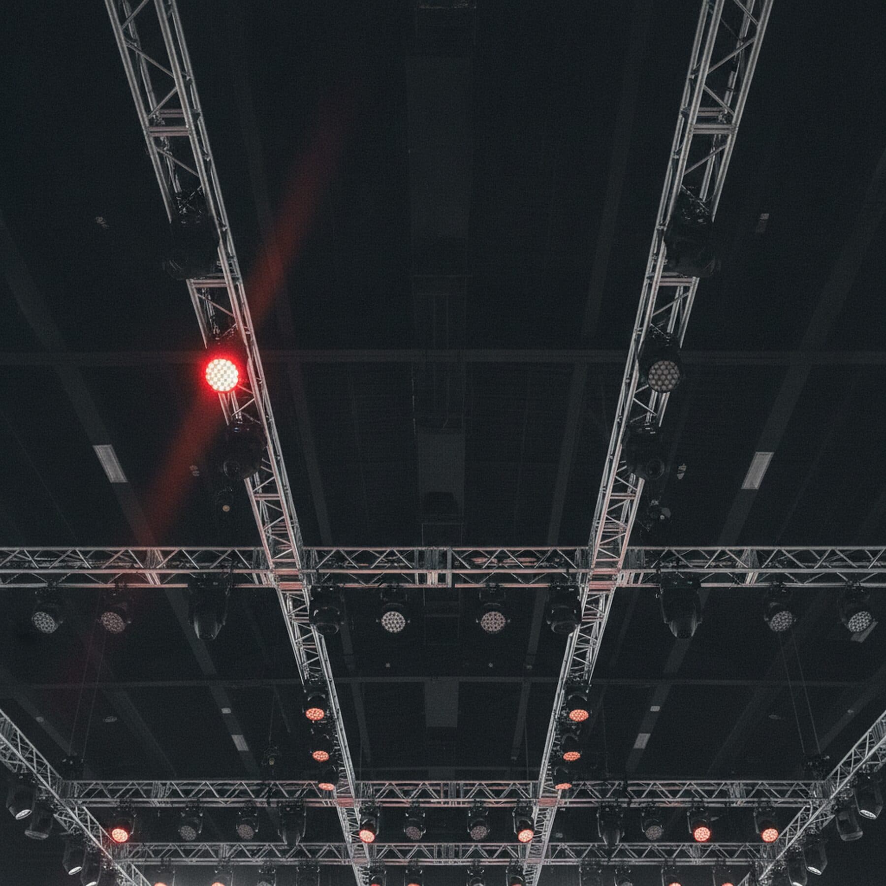Lichttraverse unter der Hallendecke mit Scheinwerfern, ein Scheinwerfer brennt zinnoberrot